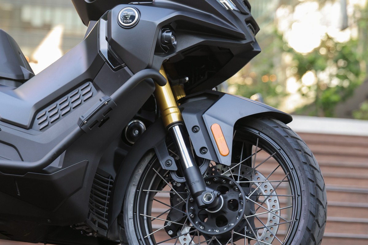 קלוז-אפ על חזית קטנוע VOGE SR450X שחור: מזלג הפוך זהוב, חישוק שפיצים קדמי עם צמיג משולב כביש-שטח ודיסק בלם