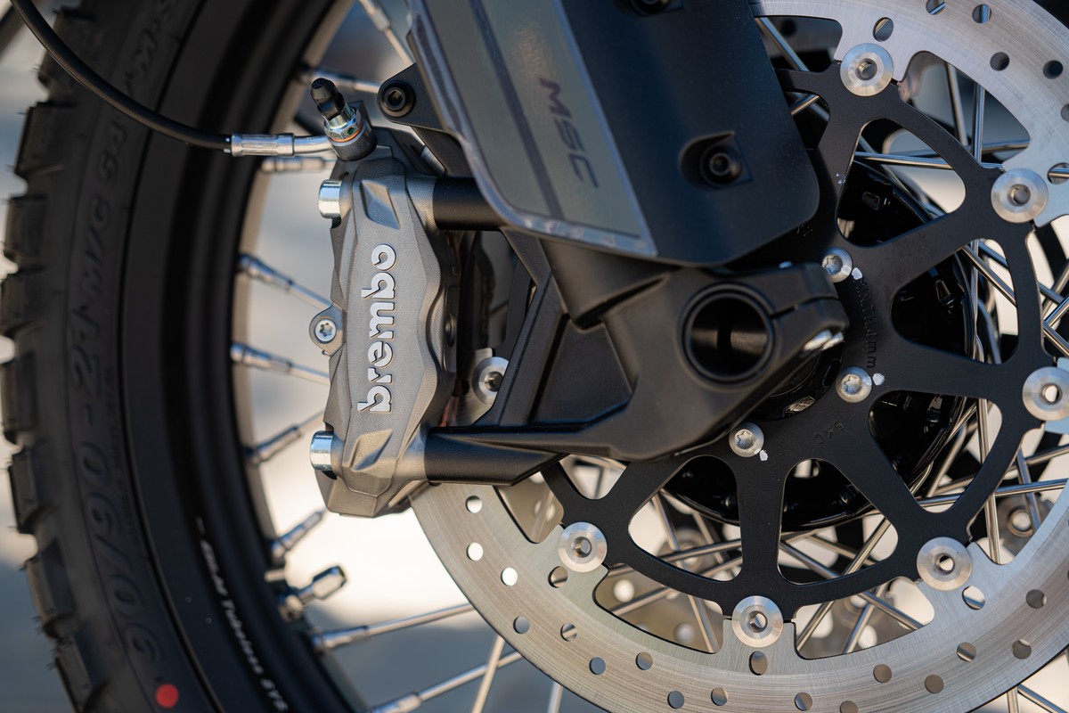 תקריב של הגלגל הקדמי של CFMOTO 1000MT-X — קליפר Brembo, דיסק הבלימה וחישוק שפיצים 21 אינץ' עם צמיג Pirelli Scorpion Rally STR